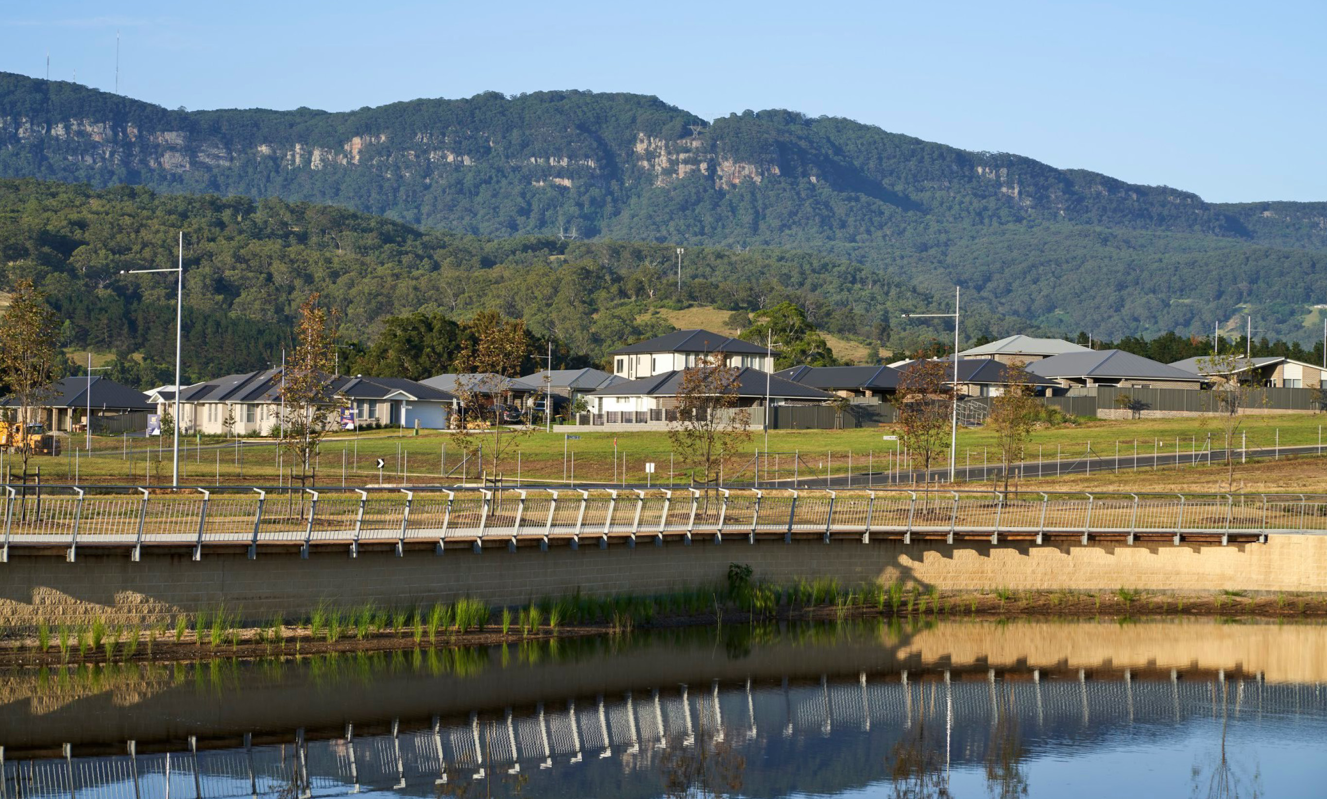 Calderwood Valley estate in Calderwood with the Illawarra escarpment in the background and a small pond in the foreground.