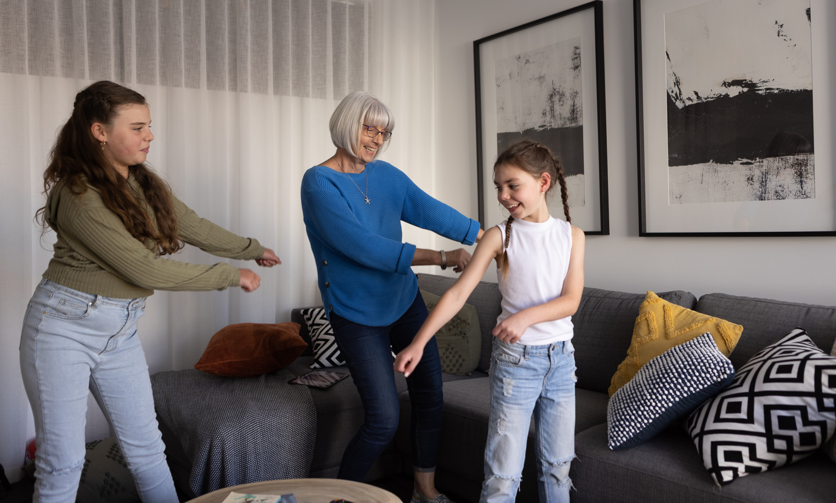 Grandma and two granddaughters in living room dancing.