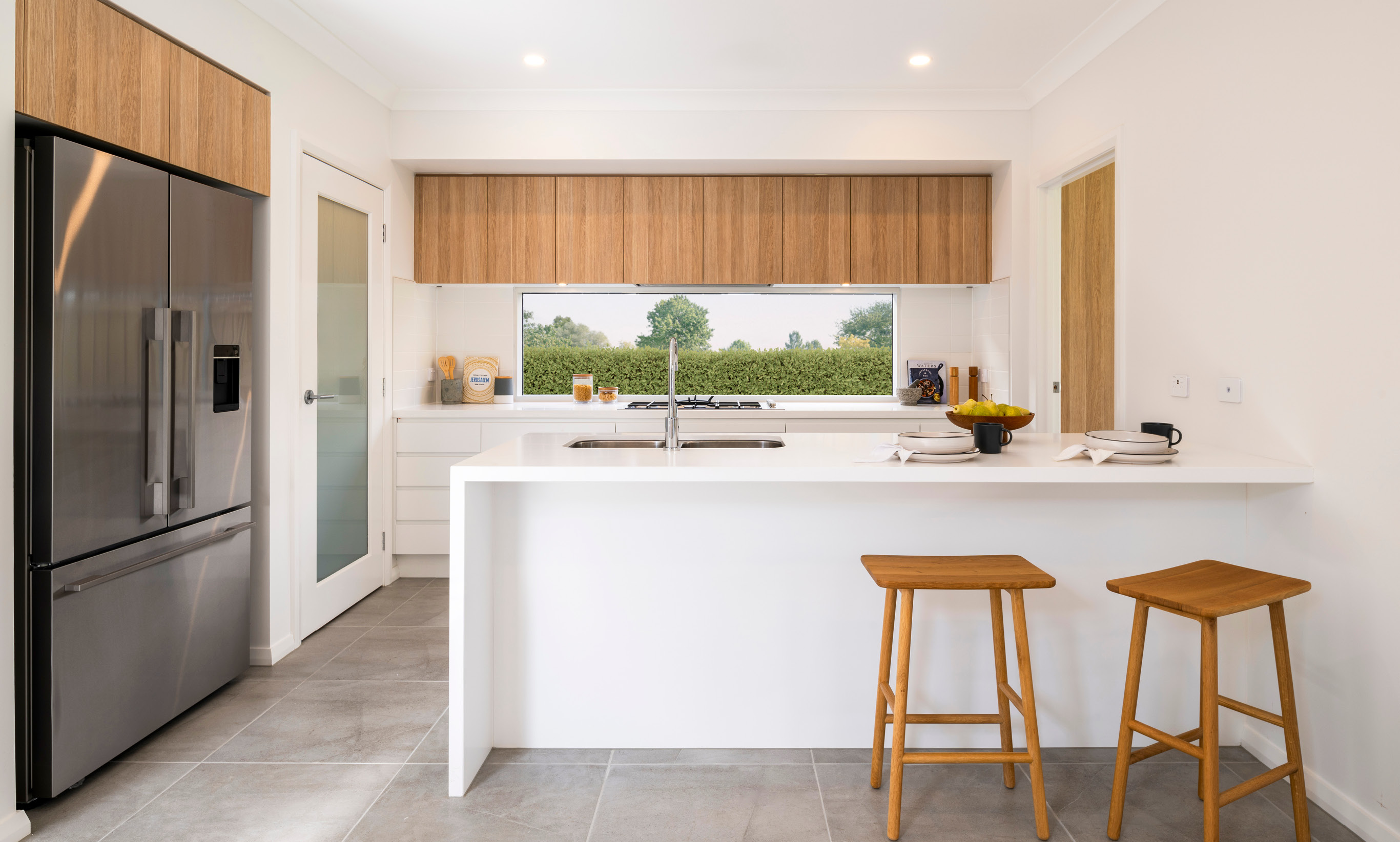 Modern kitchen design with large kitchen island, double door fridge and timber cabinetry.