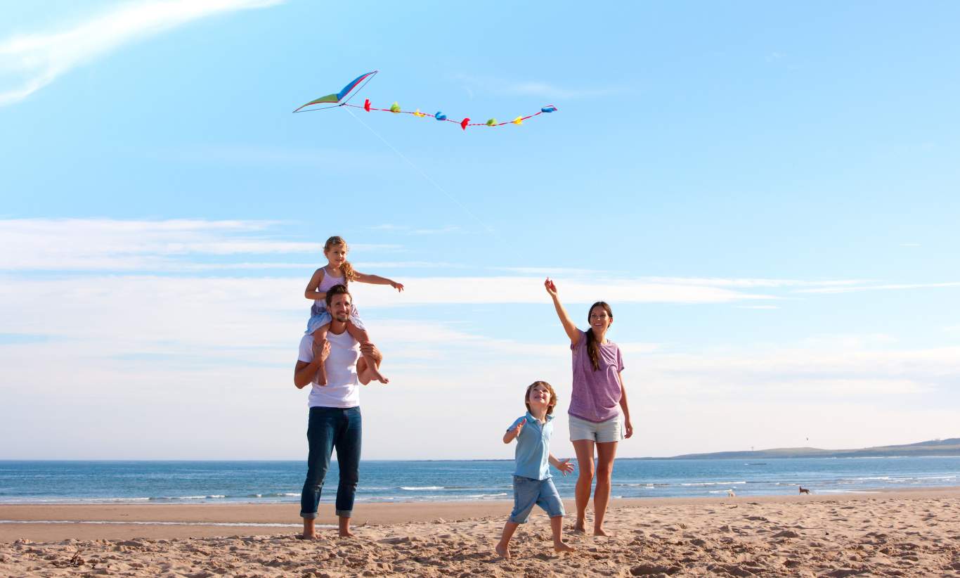 family at beach flying kite.